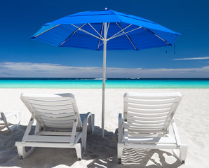 Caribbean beach with blue sun umbrellas and white beds