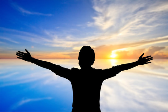 Woman raising her arms on sunset