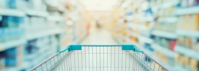 Supermarket aisle with red shopping cart - obrazy, fototapety, plakaty