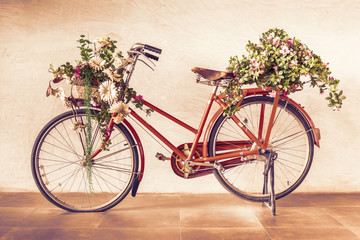Fototapeta na wymiar Vintage style of red bicycle with flower baskets parking against