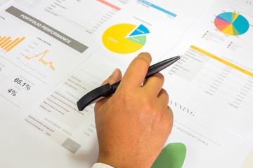 Investment planning and reporting concept. Financial planner hand holding pen over the Investment planning reporting containing colourful graph of asset allocation planning.
