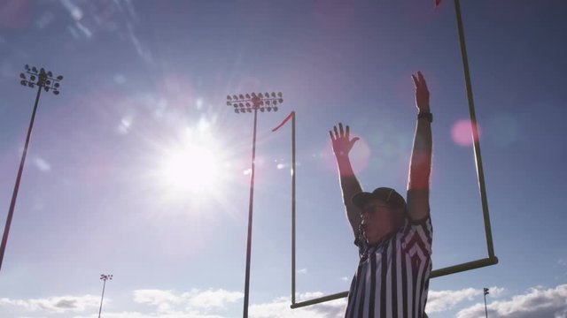 A football referee raises hands over his head for a field goal