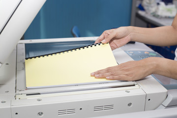 woman hands putting a sheet of paper into a copying device