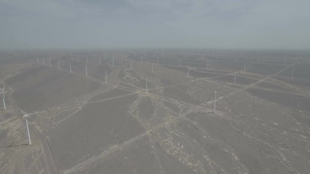 Retreating aerial shot of a massive windfarm in the deserts of Gansu in China