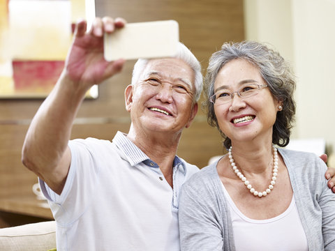 Senior Asian Couple Taking A Selfie At Home