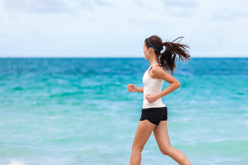 Fitness athlete training cardio running on beach. Fit sport running Asian woman runner jogging outdoor working out exercising on blue ocean water background copy space.