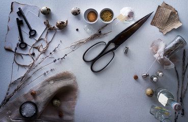 jars of powders, leaves burnt paper, scissors, quail eggs on the table. top view