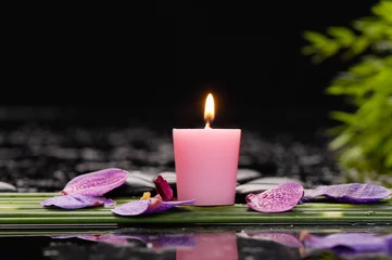 Gordijnen tranquil spa scene- orchid petals with black stones with candle ,green plant © Mee Ting