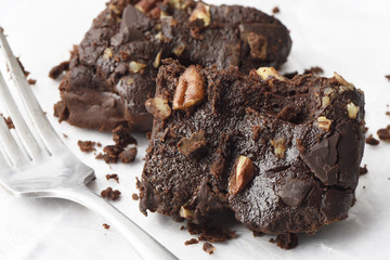 Homemade chocolate brownies with pecan nuts on a white background