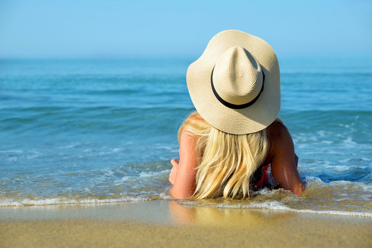 Caucasian girl with hat on the beach. Summer vacation by the sea.