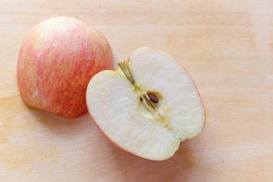 Red apple gala slice into two pieces on tamarind wood cutting board