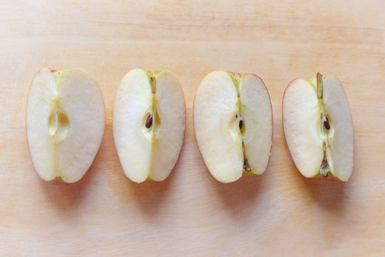 Red apple gala slice into four pieces on tamarind wood cutting board
