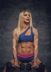 Obraz premium Female fitness model posing with dumbbells.