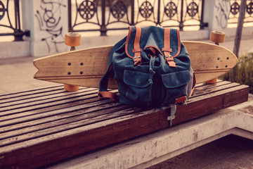 Longboard and backpack on a bench.