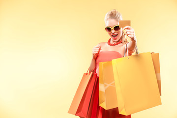 Shopping woman holding color bags and showing sale card.