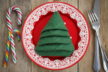Napkin folded in the shape of a Christmas tree in a red plate