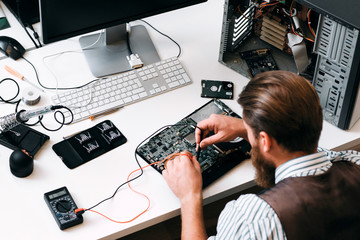 Engineer testing computer circuit with multitester. Top view on unrecognizable repairman with...