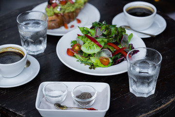 sandwich with avocado and tomatoes.Lettuce leaves the seasoned with oil and two black coffee. Lunch.