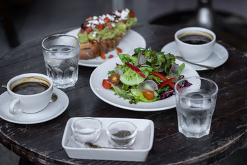 sandwich with avocado and tomatoes.Lettuce leaves the seasoned with oil and two black coffee. Lunch.