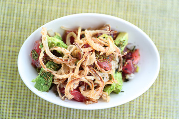 Hawaii poke bowl food. Poke bowl plate closeup on restaurant table. Fresh raw ahi tuna with fried onions, rice and avocado, sprinkled with sesame seeds. Hawaii japanese fusion food hawaiian cuisine.