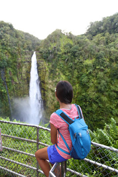 Hawaii travel tourist woman at scenic lookout viewpoint looking at Akaka falls, Big Island, Hawaii. Female hiker looking at a popular touristic hawaiian attraction beautiful waterfall.