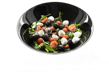 Salad with a mozzarella, a mix salad with tomatoes, olives, sheets of salad, a matsarel. On a white background in black ware