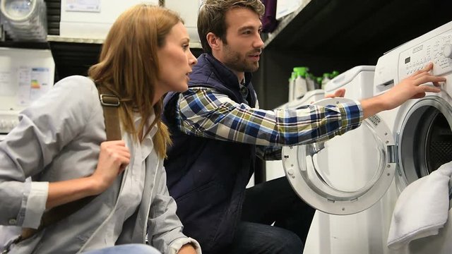 Seller helping customer with choosing washing machine