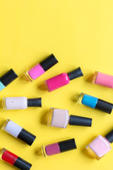 lot of bottles nail polish on yellow background top view