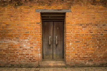 Fototapeta na wymiar The orange brick wall and the old door in the middle of the wall in Kathmandu, Nepal.