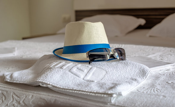 hat, towel and sunglasses on the bed in the hotel