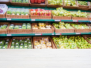 Wooden empty table in front of blurred supermarket vegetables shelf
