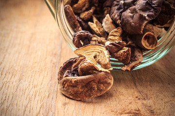 Dry mushrooms in jar on wooden table.