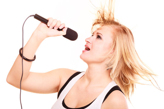 Blonde woman singing to microphone, profile view