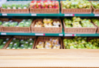 Wooden empty table in front of blurred supermarket fruits shelf