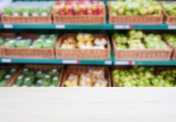 Wooden empty table in front of blurred supermarket vegetables shelf