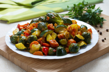 Fried vegetables on white plate and wooden desk