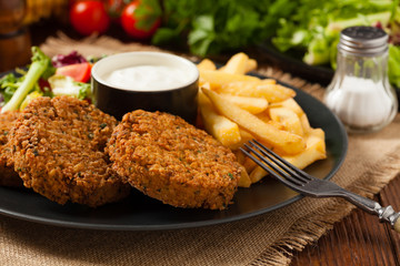 Serving of falafel and chips served on a black plate with sauce.