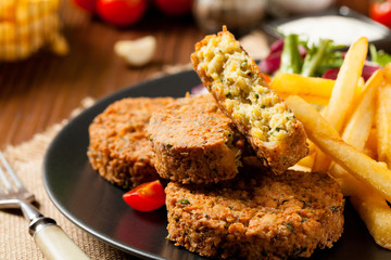Serving of falafel and chips served on a black plate with sauce.