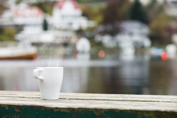 A cup of tea standing on a wooden table. Fisherman's Wharf, the pier. Large fishing boats. Shipyard for repair of ships, fishing boats.