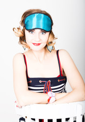 beautiful young woman in a striped dress and points for sleep, sitting on a chair and posing. sleeping eye covering mask