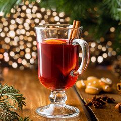 Glass of mulled wine by Christmas tree. Traditional delicious drink for New Year party