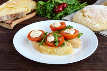 Bruschetta with arugula, tomatoes, mozzarella, olive oil on slices of chiabatta. Light breakfast.