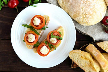 Bruschetta with arugula, tomatoes, mozzarella, olive oil on slices of chiabatta. Light breakfast. The top view