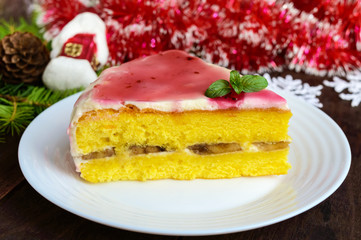 Sponge cake with a layer of banana, milk cream and cranberry syrup. Holiday dessert for Christmas.