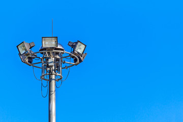 Spotlight and the sky. Large tall high outdoor stadium spotlights. spotlights lighting tower at sport arena stadium. Halogen spotlights and blue sky.