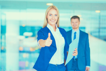 Business woman standing in foreground , showing ok