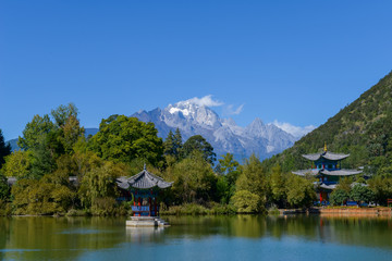 Fototapeta na wymiar Black Dragon Pool to the Five Phoenix Tower and the Five Holes Bridge. In the background is Jade Dragon Snow Mountain. The Old Town of Lijiang is located in Lijiang City, Yunnan, China.