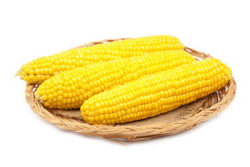 Corn cobs on a wicker plate on a white