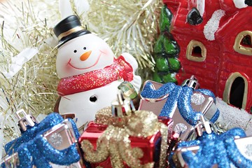 Merry Christmas or Happy New Year background concept : Cute snowman, christmas gifts box or presents and Santa Claus house on gold streamer or tinsel background