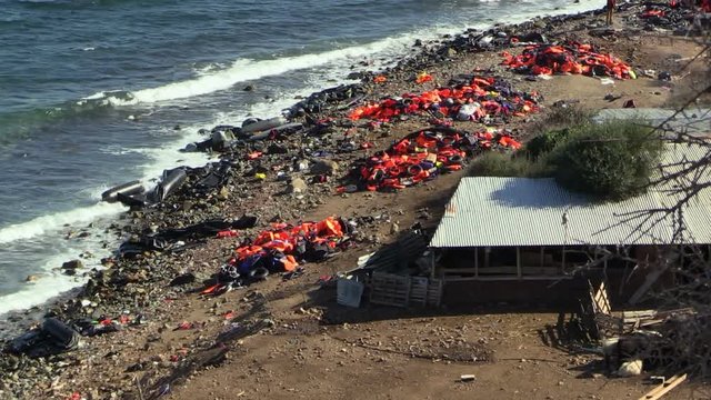LESVOS, GREECE - NOV 2, 2015: Abandoned by the refugees belongings and life jackets on the shore.
